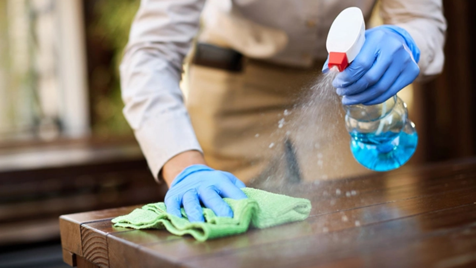 Closeup of waitress disinfecting tables at outdoor cafe